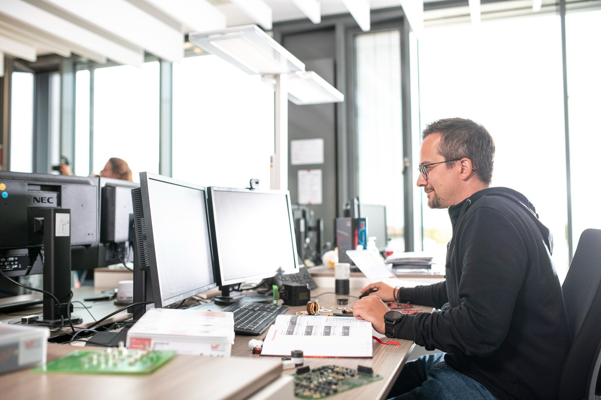 Computer Arbeit Mann sucht am PC nach Produkten mithilfe von EV-Boards und Katalogen
